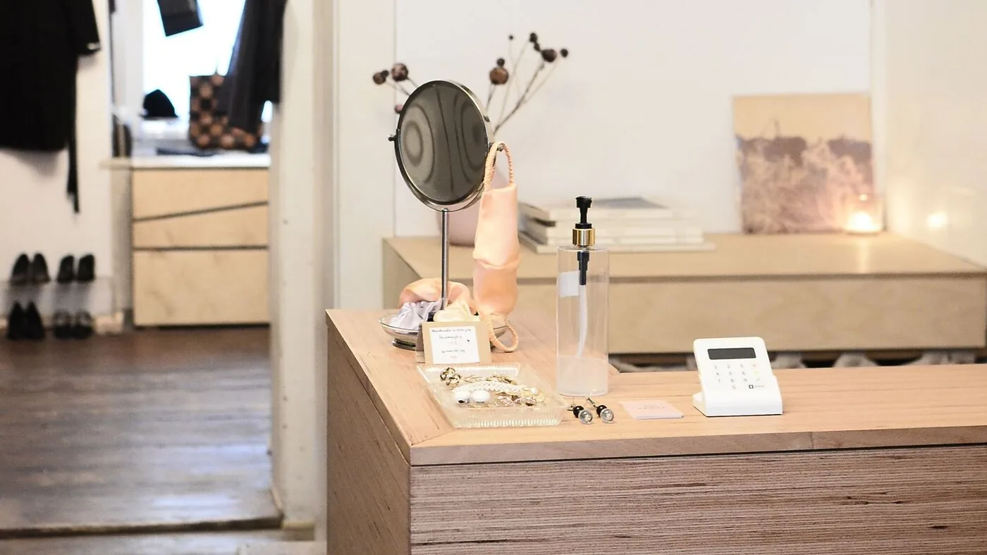 A small shop's wooden checkout counter with jewelry and a card reader