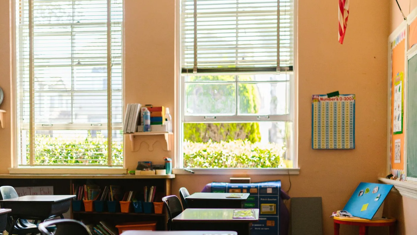 An empty classroom with desks and an American flag